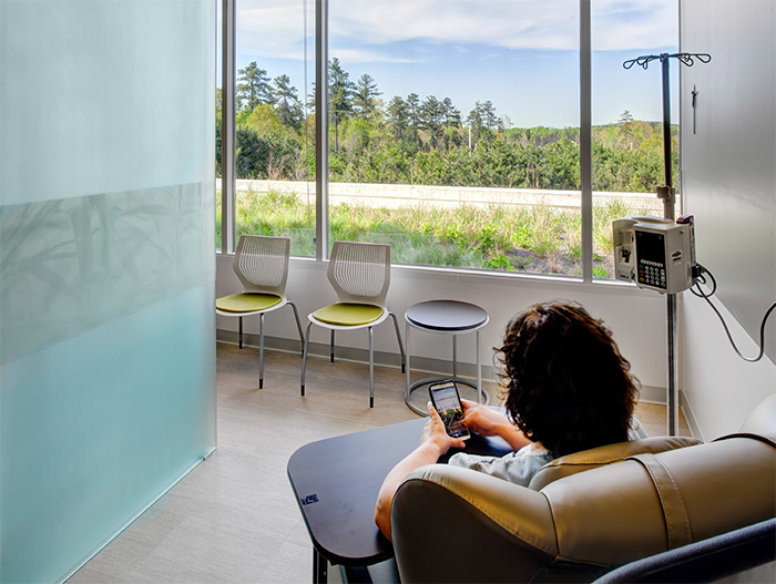 Infusion treatment areas sit at the perimeter of the building, offering patients natural light and views of the surrounding mountains. In addition, movable walls can be closed by patients who wish to have privacy, or opened to connect with others receiving treatment. Featured: MultiGeneration by Knoll<sup>®</sup> Stacking Chairs